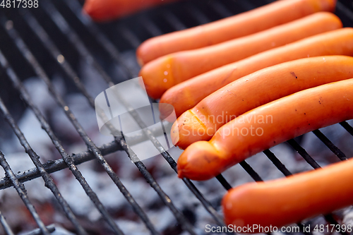 Image of meat sausages roasting on hot brazier grill