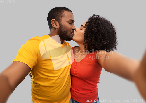 Image of african american couple taking selfie and kissing