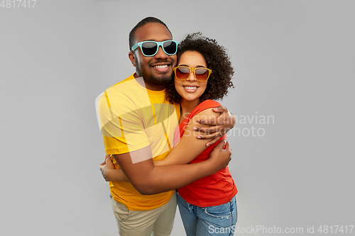 Image of happy african couple in sunglasses hugging