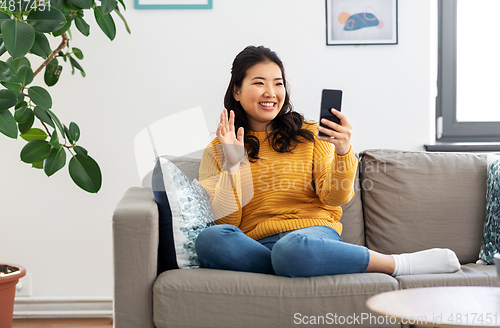 Image of woman with smartphone having video call at home