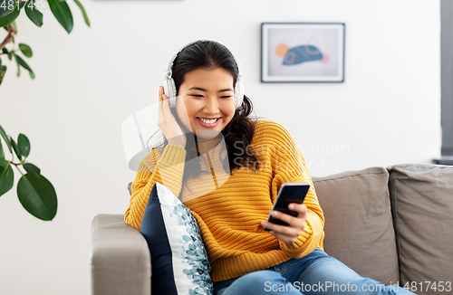 Image of asian woman with headphones and smartphone at home