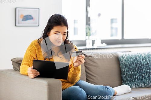 Image of asian woman with tablet pc and credit card at home