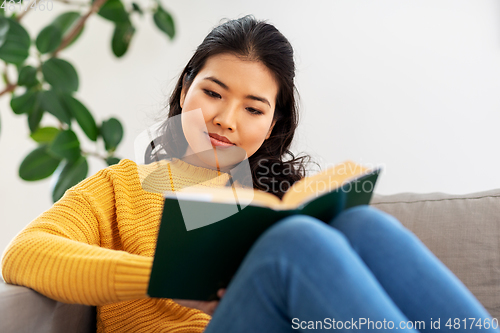 Image of asian young woman reading book at home