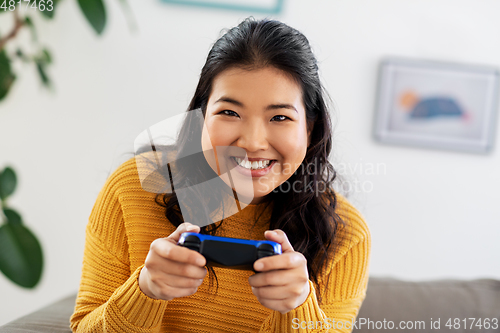 Image of asian woman with gamepad playing game at home