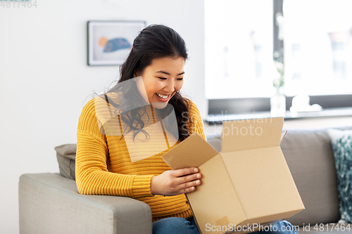 Image of happy asian young woman with parcel box at home