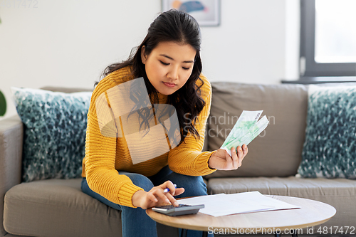 Image of woman with money, papers and calculator at home