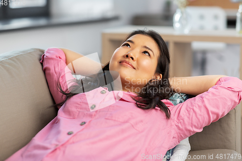 Image of asian woman lying on sofa and dreaming at home