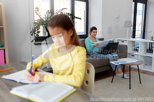 Image of mother working and daughter studying at home