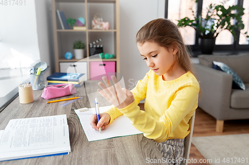 Image of student girl with book writing to notebook at home