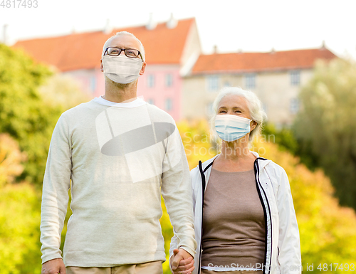 Image of senior couple in protective medical masks outdoors