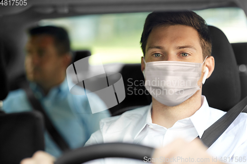 Image of taxi driver in face protective mask driving car