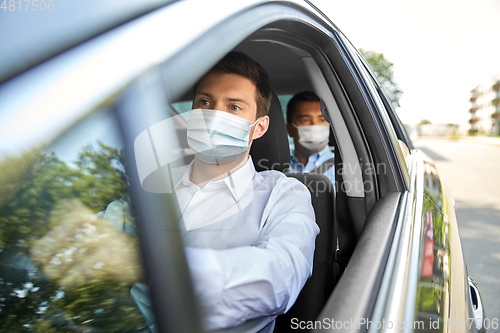 Image of taxi driver in face protective mask driving car