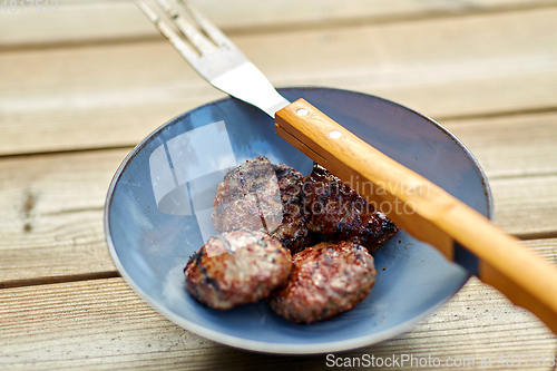 Image of roasted meat cutlets on plate with barbeque fork