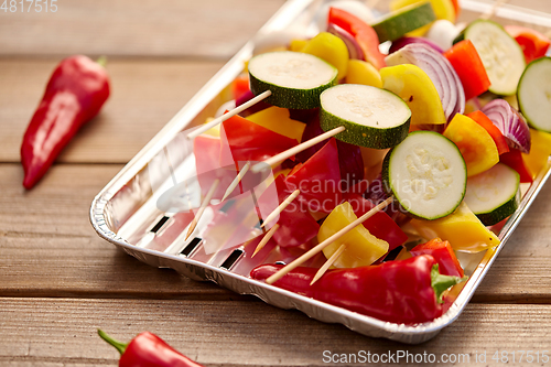 Image of close up of vegetables on skewers on foil grill
