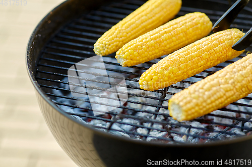 Image of close up of corn roasting on grill outdoors