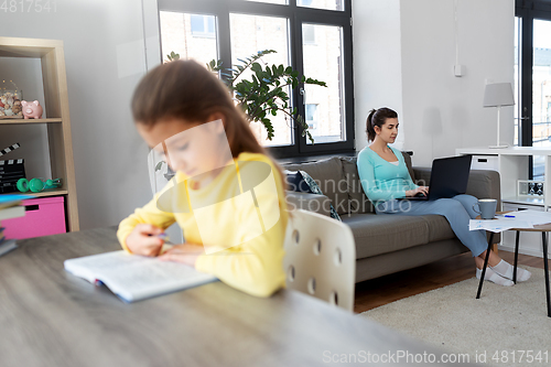 Image of mother working and daughter studying at home