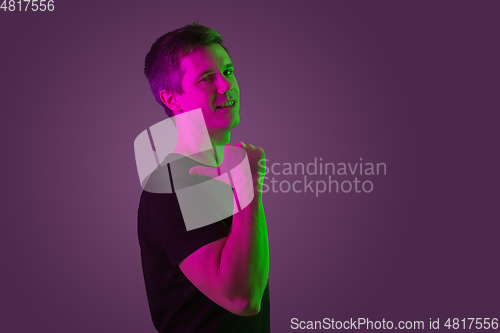 Image of Caucasian man\'s portrait isolated on purple studio background in neon light