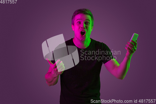 Image of Caucasian man\'s portrait isolated on purple studio background in neon light