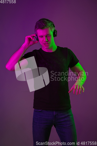 Image of Caucasian man\'s portrait isolated on purple studio background in neon light