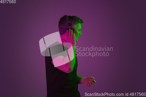 Image of Caucasian man\'s portrait isolated on purple studio background in neon light