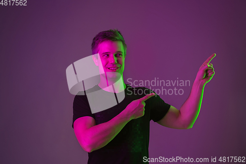 Image of Caucasian man\'s portrait isolated on purple studio background in neon light