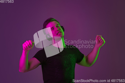Image of Caucasian man\'s portrait isolated on purple studio background in neon light