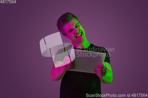 Image of Caucasian man\'s portrait isolated on purple studio background in neon light