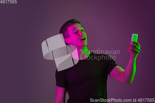 Image of Caucasian man\'s portrait isolated on purple studio background in neon light
