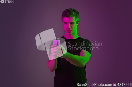 Image of Caucasian man\'s portrait isolated on purple studio background in neon light