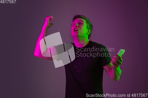 Image of Caucasian man\'s portrait isolated on purple studio background in neon light