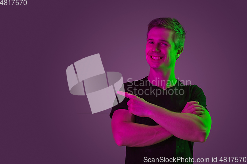 Image of Caucasian man\'s portrait isolated on purple studio background in neon light