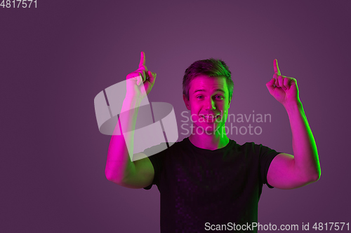Image of Caucasian man\'s portrait isolated on purple studio background in neon light