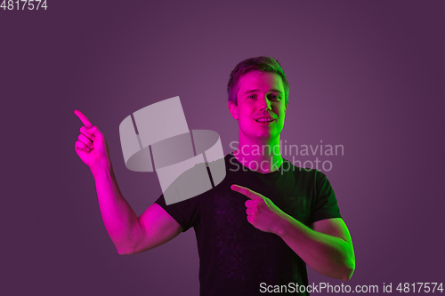 Image of Caucasian man\'s portrait isolated on purple studio background in neon light