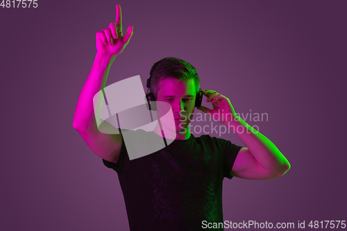 Image of Caucasian man\'s portrait isolated on purple studio background in neon light