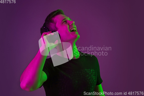 Image of Caucasian man\'s portrait isolated on purple studio background in neon light