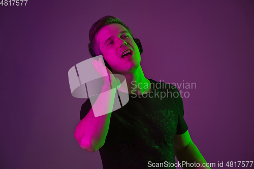 Image of Caucasian man\'s portrait isolated on purple studio background in neon light