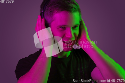 Image of Caucasian man\'s portrait isolated on purple studio background in neon light