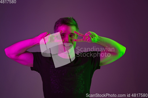 Image of Caucasian man\'s portrait isolated on purple studio background in neon light