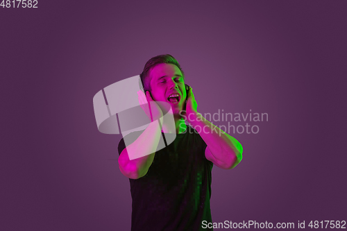 Image of Caucasian man\'s portrait isolated on purple studio background in neon light