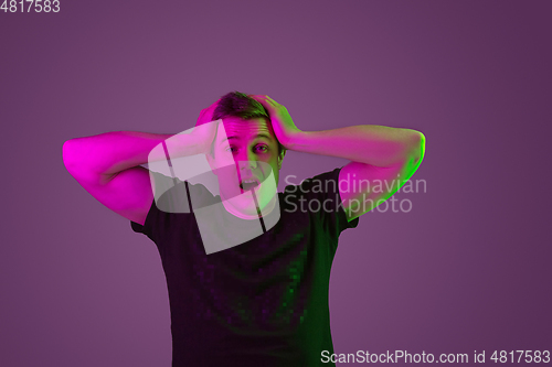 Image of Caucasian man\'s portrait isolated on purple studio background in neon light