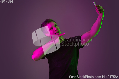 Image of Caucasian man\'s portrait isolated on purple studio background in neon light