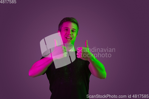 Image of Caucasian man\'s portrait isolated on purple studio background in neon light