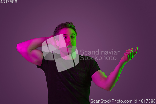 Image of Caucasian man\'s portrait isolated on purple studio background in neon light