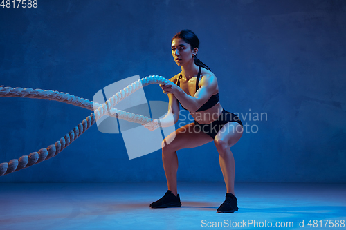 Image of Caucasian young female athlete practicing on blue studio background in neon light