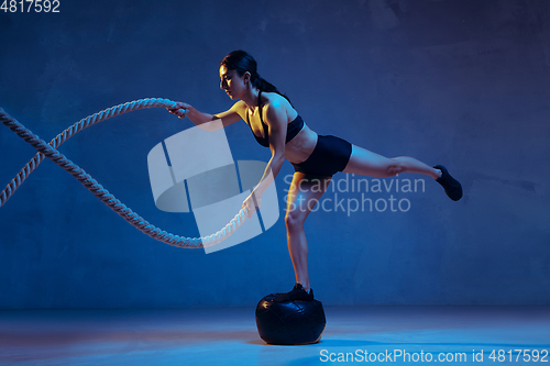 Image of Caucasian young female athlete practicing on blue studio background in neon light