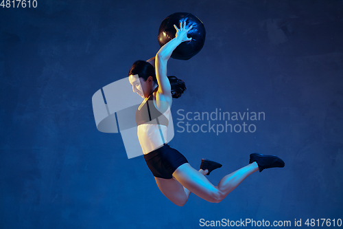 Image of Caucasian young female athlete practicing on blue studio background in neon light