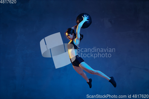 Image of Caucasian young female athlete practicing on blue studio background in neon light