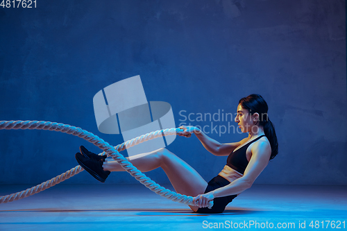 Image of Caucasian young female athlete practicing on blue studio background in neon light