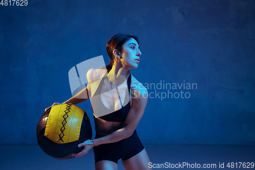 Image of Caucasian young female athlete practicing on blue studio background in neon light