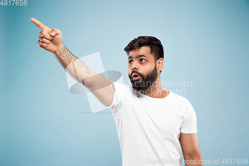 Image of Half-length close up portrait of young man on blue background.